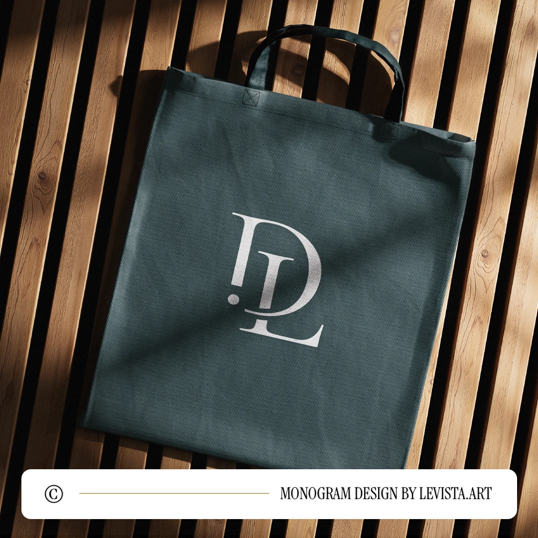 White DL logo design as minimalist monogram on a rich green textile bag lying on a brown wooden surface for sophisticated branding, stationery, high-quality print and décor