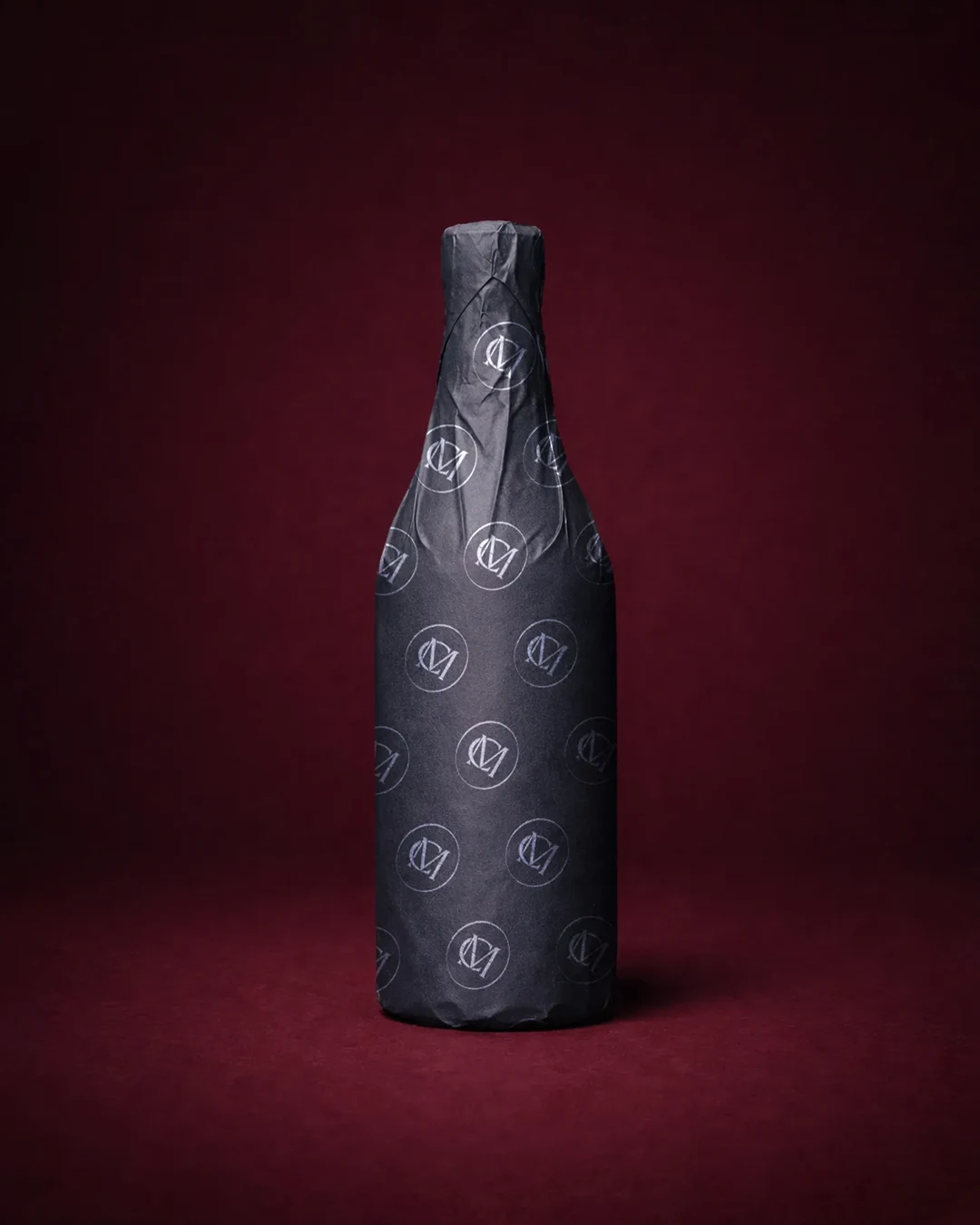 vertical wine bottle packaging design Vertical view of a wine bottle wrapped in designer paper with a custom monogram logo
